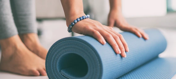 woman rolling exercise mat in living room