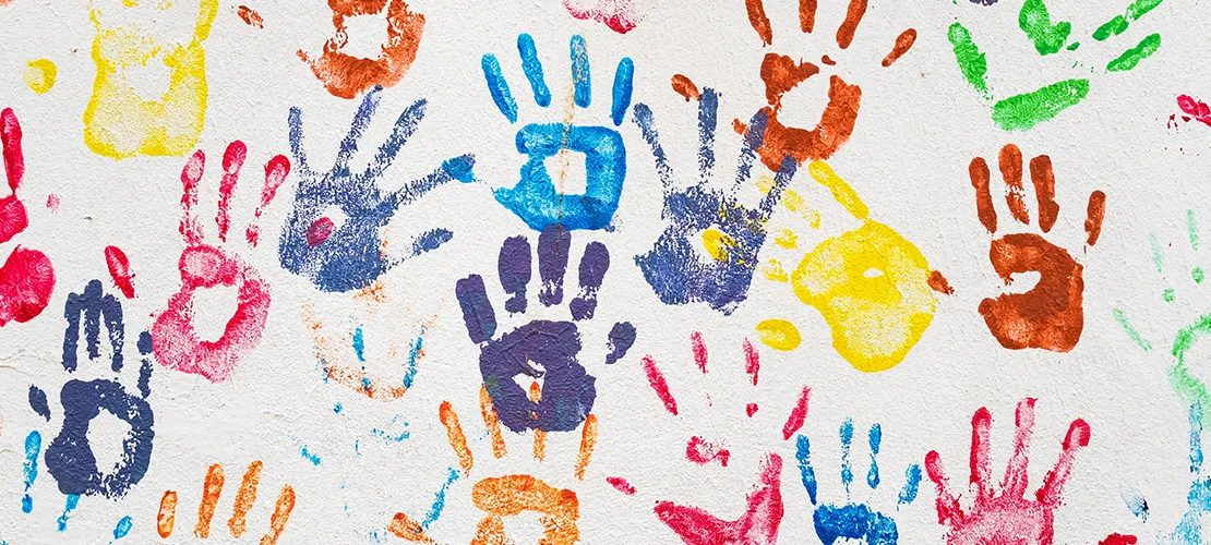 Different color handprints on a white wall.