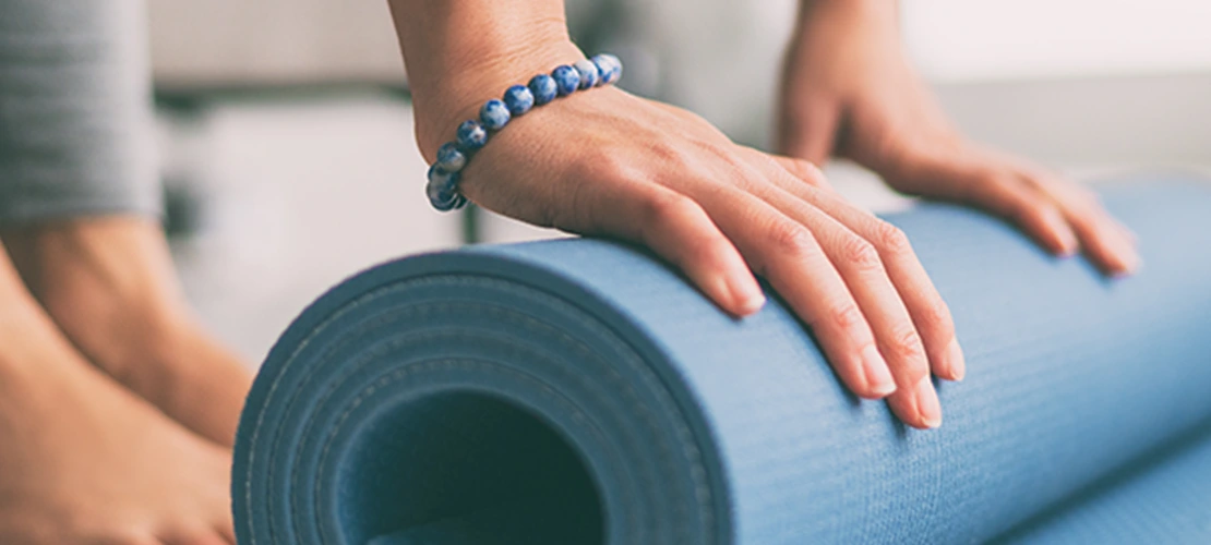 Close up on a woman rolling up her yoga mat
