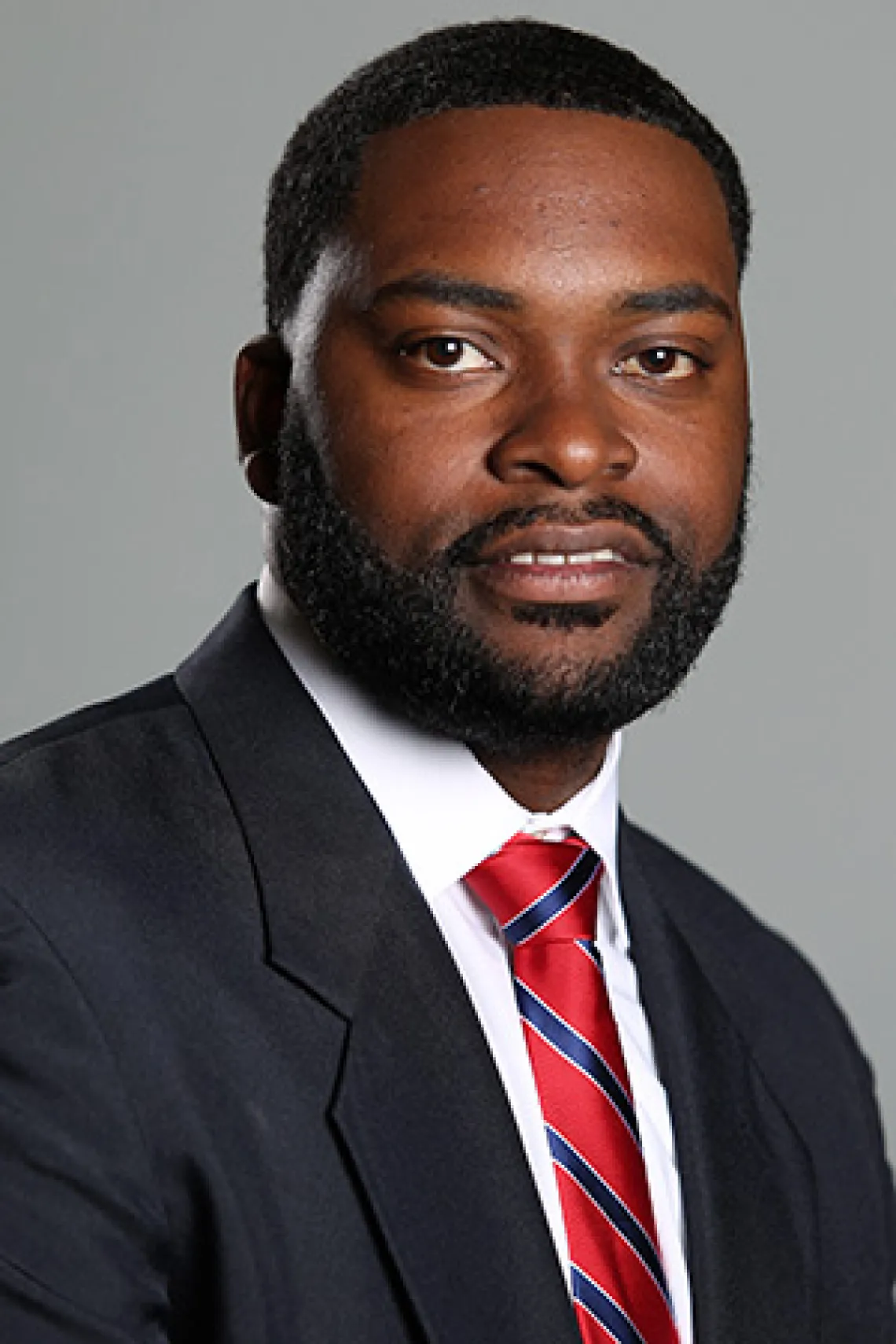 Thomas Harris wearing a black suit and red-and-blue tie