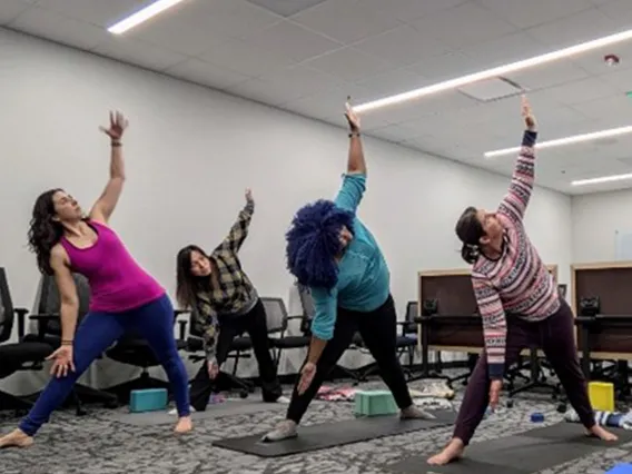 Employees practicing yoga, triangle pose