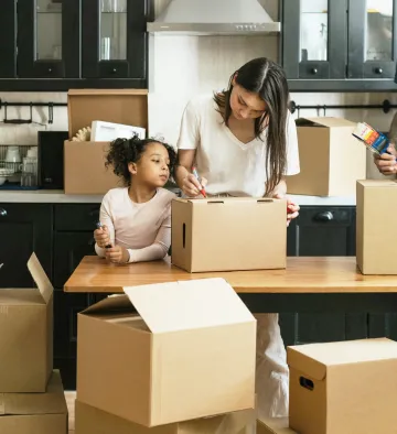 A woman and a child packing up boxes in a kitchen A woman and a child packing up boxes in a kitchen